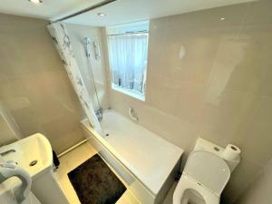 y baño con 2 aseos, ducha y lavamanos. en Spacious 1-bedroom Flat in Sutton (South London), en Sutton