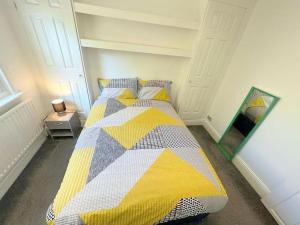 a bedroom with a bed with a yellow and gray quilt at Spacious 1-bedroom Flat in Sutton (South London) in Sutton