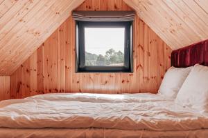 Bett in einem Holzzimmer mit Fenster in der Unterkunft WymarzONE- domki w górach z kominkiem i jacuzzi in Wieściszowice
