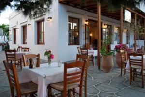 um restaurante com uma mesa e cadeiras e uma mesa e uma espreguiçadeira em Artemon Hotel em Artemonas