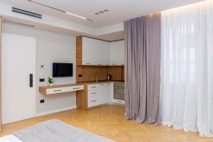 a kitchen with white cabinets and a large window at Hotel Saly in Durrës