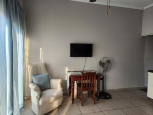a living room with a chair and a table and a television at Sunny Guest Room in Boksburg