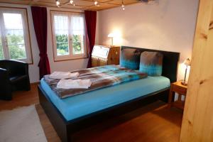a bedroom with a bed with blue sheets and two windows at Family Landhaus Birwinken in Berg