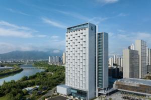 un grand bâtiment blanc à côté d'une rivière dans l'établissement Sheraton Taizhou, à Taizhou