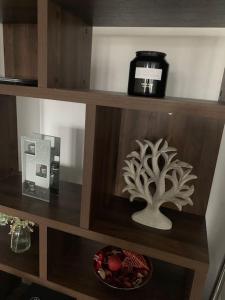 a shelf with a clock and a tree on it at Two bed flat stylishly furnished in Purfleet