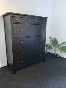 a black dresser with a potted plant next to it at Two bed flat stylishly furnished in Purfleet