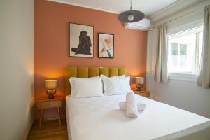 a bedroom with a white bed with orange walls at Acropolis View - 500m Metro - At Historical Center in Athens