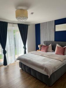 Un dormitorio con una cama grande con paredes azules y una lámpara de araña. en Luxury Apartment near Munich Airport - Therme ED - Parking en Berglern