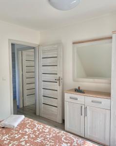 a bedroom with a large mirror and white cabinets at Apartamenty Golf Dyndeby in Neksø