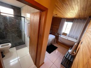 uma casa de banho com uma banheira, um chuveiro e um lavatório. em Recanto Ar da Serra em São Joaquim