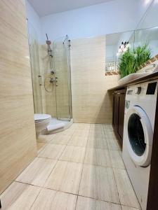 een badkamer met een douche en een wasmachine bij Apartament przy Rynku in Poznań