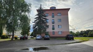 un gran edificio rosa con coches aparcados en un aparcamiento en Suk apartmán 24, en Suchdol nad Lužnicí