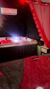 a room with a bed and a tub with a red curtain at Douceur d’une nuit (studio avec jaccuzi privatif) in Vitrolles