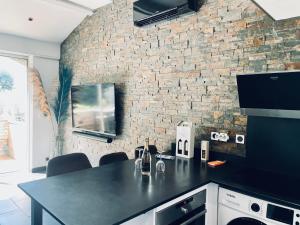 uma cozinha com um balcão preto e uma parede de tijolos em Appartement moderne tout à pied plages, commerces em Saint-Cyr-sur-Mer