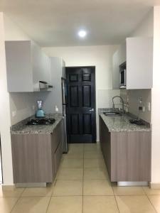 a kitchen with white cabinets and a black door at ymssjamg in Mazatlán