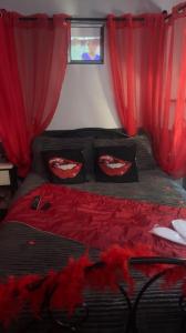 a bedroom with a bed with red drapes at Douceur d’une nuit (studio avec jaccuzi privatif) in Vitrolles