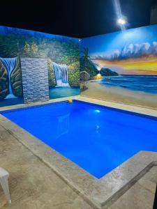 uma grande piscina azul com uma pintura na parede em R.G sol 2 em Pantoja