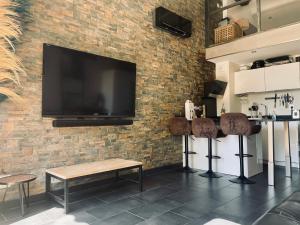 a bar with two stools and a television on a brick wall at LA CASA PALMITO appartement moderne coté mer in Saint-Cyr-sur-Mer +13 photos