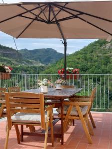 una mesa de madera y sillas bajo una sombrilla en el patio en B&B Donnini Firenzuola, en Casetta di Tiara