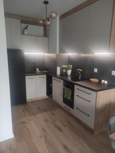uma cozinha com armários brancos e um balcão preto em Apartament Leśna Mandala em Augustów