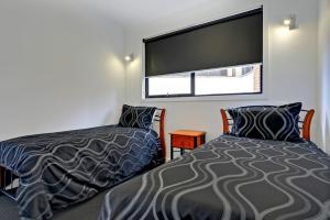 1 dormitorio con 2 camas y ventana grande en Burnie by the Bay Apartments, en Burnie