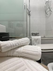 een badkamer met witte handdoeken op een aanrecht en een bad bij Claire Rose B&B in Matera