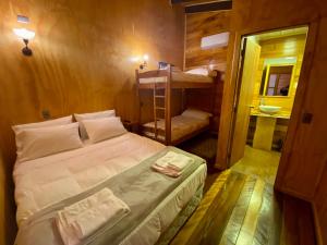 ein Schlafzimmer mit einem Bett und einem Etagenbett sowie ein Badezimmer in der Unterkunft Hostal Caulle in Río Bueno