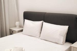 a bed with white pillows and a black headboard at Φιλόξενο σπίτι στο Βόλο in Volos