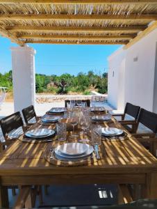 a wooden table with glasses and plates on it at Villa Pupetta Ostuni 4 bedrooms 4 bathrooms - swimming pool in Ostuni