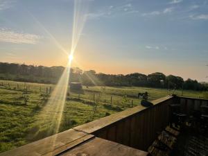 una vista de un campo con el sol brillando en el cielo en Cushieston’s Shepherd’s Hut en Meikle Wartle