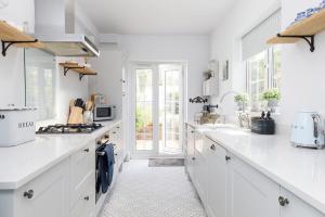una cocina blanca con encimeras blancas y electrodomésticos blancos en The Kept Cottage, en Hassocks