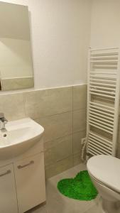 een badkamer met een toilet, een wastafel en een groen tapijt bij Rekreačná Chata in Jakubovany