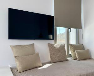 a living room with pillows and a tv on the wall at Casa di Amerissa Premium Accommodation in Skiros