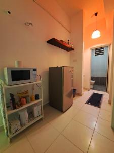 eine Küche mit einem Kühlschrank und einer Mikrowelle in der Unterkunft LED Homestay in Shah Alam