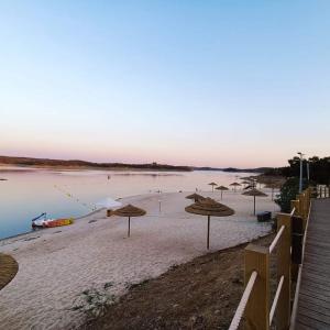 una playa con sombrillas y un barco en el agua en A Casa do Mestre Lau - no coração do Alentejo, en Terena