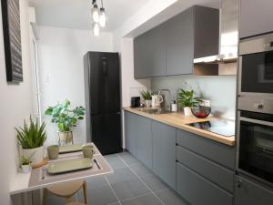 a kitchen with gray cabinets and a black refrigerator at Clichy-Levallois Bords de Seine in Clichy