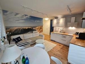 Una cocina y una sala de estar con un sofá y una mesa. en Słoneczny apartament, en Jurata