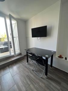 een kamer met een tafel en een tv aan de muur bij Appartement 4 personnes, aéroport Marseille in Marignane