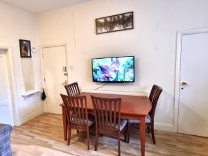 a dining room table with chairs and a tv on the wall at Spacious Flat Near Rochdale Centre Self Check-in Free Parking & Fast Wi-Fi in Rochdale