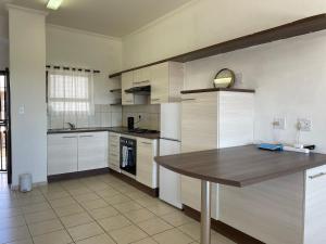 a kitchen with white cabinets and a wooden table at H&H Self-catering in Windhoek