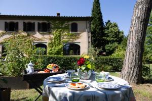 un tavolo con piatti di cibo sopra con una casa sullo sfondo di Villa la Ginestra - Charming Country Rooms a Subbiano