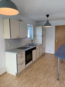 a kitchen with white cabinets and a blue table at Harmony Apartment, your holiday home in Rust with balcony & river-view, 5min to Europa-Park in Rust