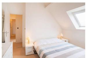 una camera da letto bianca con un letto e una finestra di Appart duplex hypercentre 8 pers , petite vue mer a Le Touquet-Paris-Plage