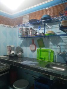 a kitchen with a sink and a shelf with pots and pans at taghazout agadir appartement familiale in Taghazout