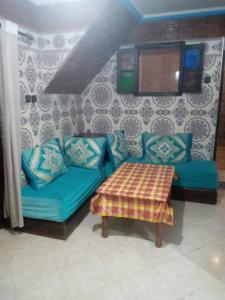 a living room with a blue couch and a table at taghazout agadir appartement familiale in Taghazout