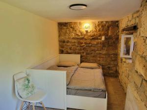 1 dormitorio pequeño con 1 cama en una pared de piedra en Maison des biches, en Saint-Jean-et-Saint-Paul