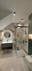 ein Bad mit einer Dusche, einem Waschbecken und einem Spiegel in der Unterkunft Kameralny Apartament nieopodal Gdyni parking NEW in Pogórze