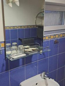 Baño de azulejos azules con lavabo y espejo en Lejas, en Lapmežciems