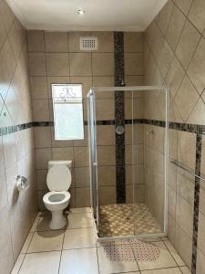 a bathroom with a toilet and a shower stall at Caribe Accommodation and Conferences in Pietermaritzburg