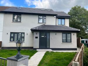 une maison blanche avec un toit noir dans l'établissement Super deluxe apartment, à Barnet